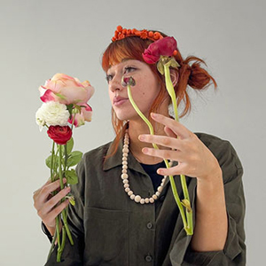 A girl with a green shirt holding flowers and orange crown